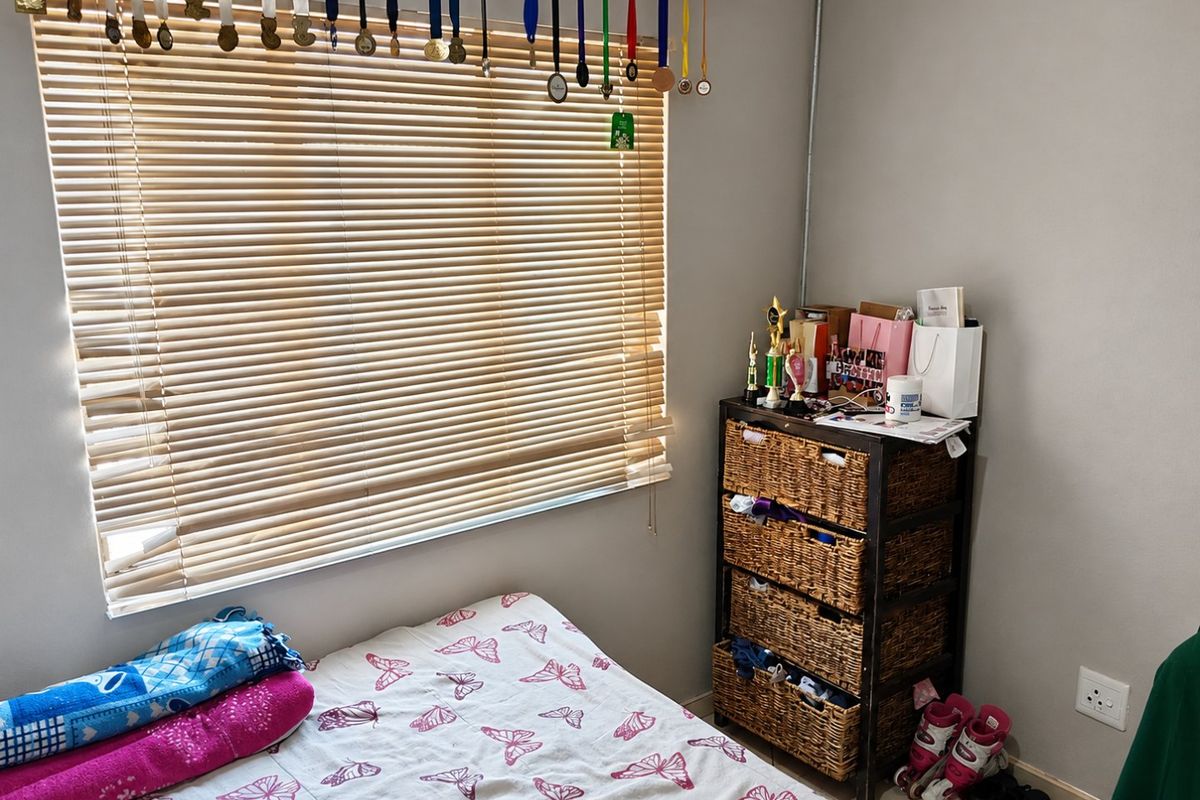 A bedroom featuring neutral wall finishes, a window with fitted venetian blinds, and standard electrical infrastructure.