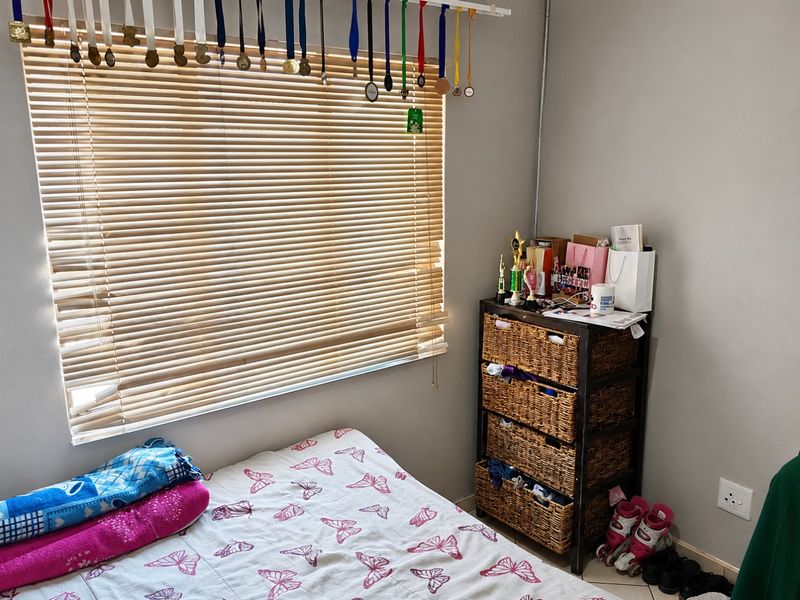 A bedroom featuring neutral wall finishes, a window with fitted venetian blinds, and standard electrical infrastructure.