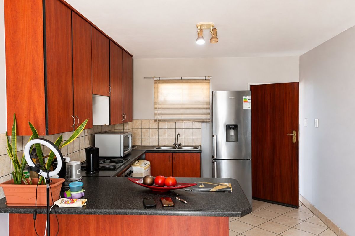 Functional kitchen featuring laminate cabinetry, dark countertops, tiled backsplash, and ceramic flooring, providing a practical workspace with integrated appliances.