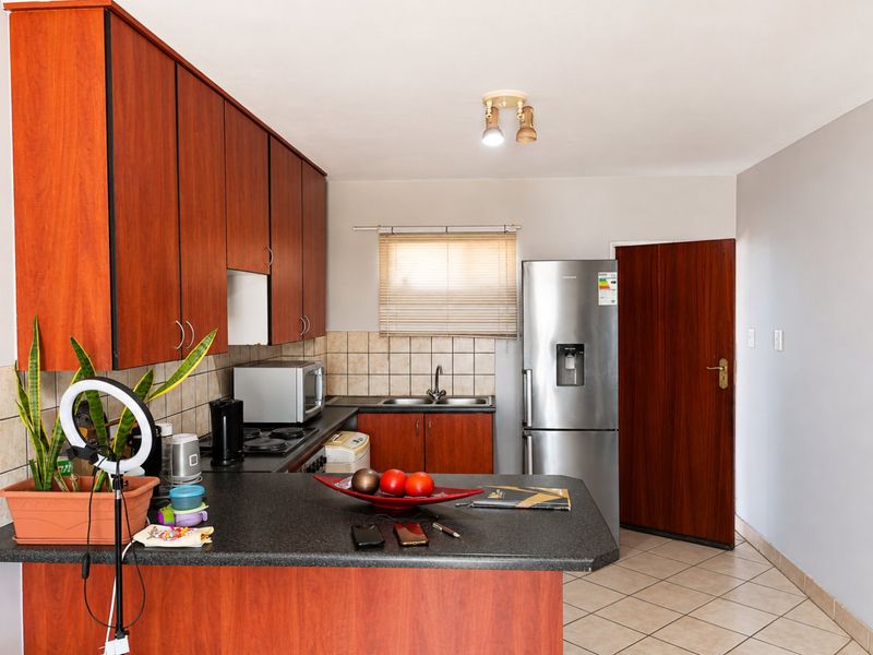 Functional kitchen featuring laminate cabinetry, dark countertops, tiled backsplash, and ceramic flooring, providing a practical workspace with integrated appliances.