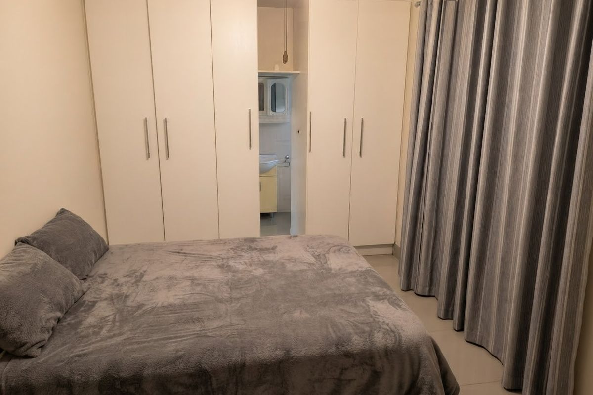 Bedroom featuring built-in cupboards and a small integrated en-suite vanity area with tiled flooring.