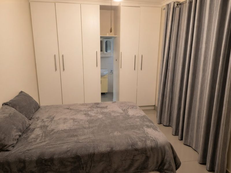 Bedroom featuring built-in cupboards and a small integrated en-suite vanity area with tiled flooring.