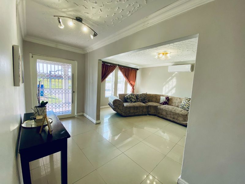 Open-plan living area featuring polished porcelain floor tiles, decorative ceiling finishes, and a wall-mounted air conditioning unit.