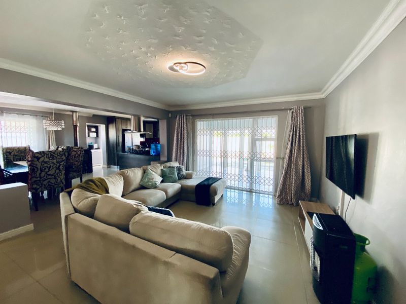 Spacious open-plan living area featuring tiled floors, textured ceiling detail, and seamless flow to the kitchen and outdoor access via sliding doors.