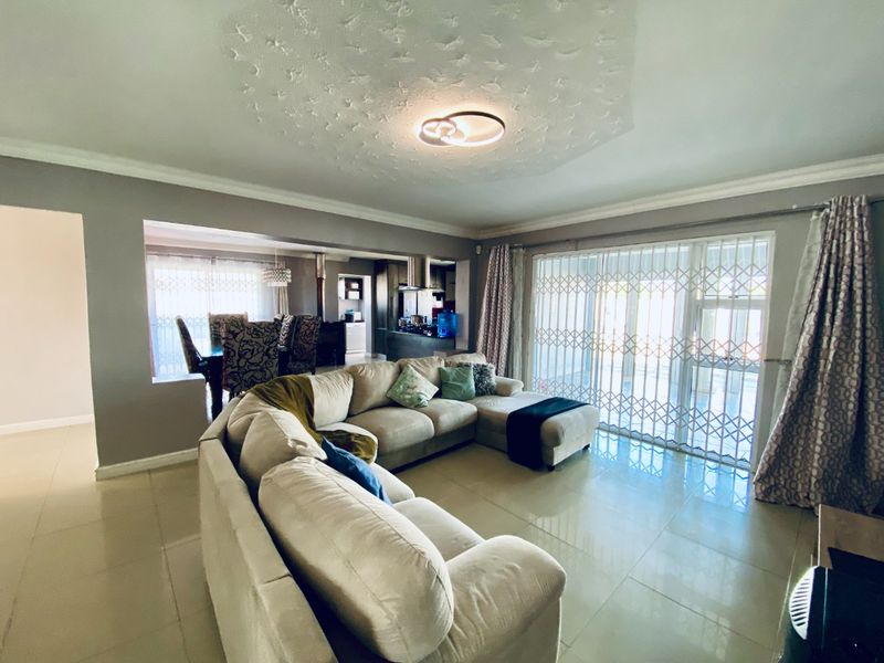 Spacious open-plan living area featuring large porcelain floor tiles, sliding glass doors with security gates, and a seamless flow into the kitchen and dining space.