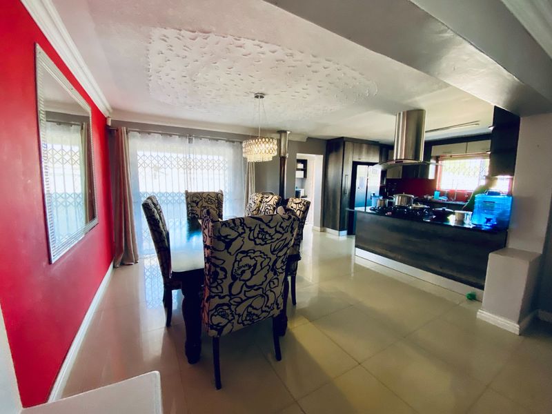 Open-plan living and dining area featuring a modern kitchen with a central island, extractor fan, and tiled flooring throughout.
