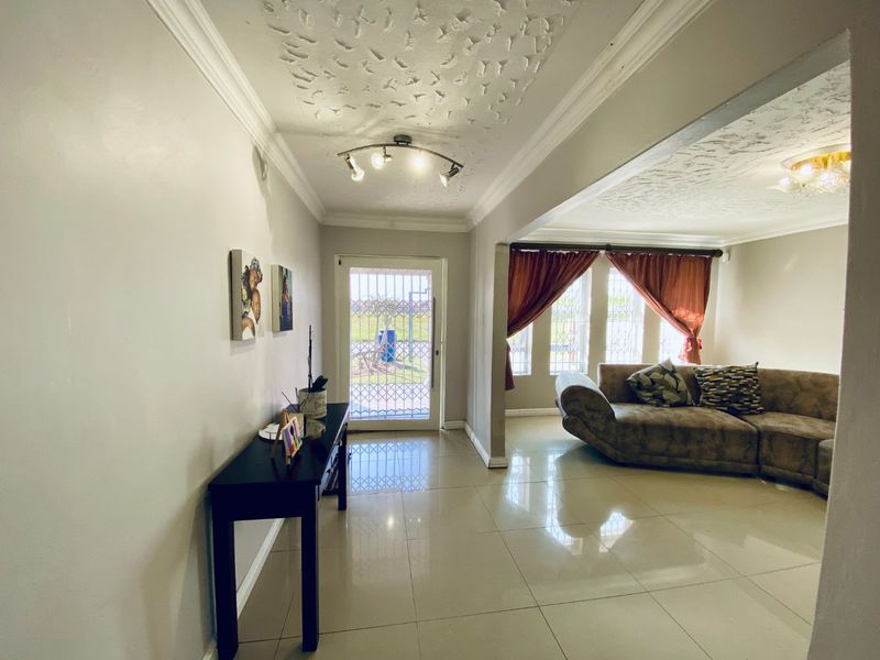 Open plan living area featuring polished porcelain floor tiles, textured ceilings with decorative coving, and a secure entrance door with security gate.