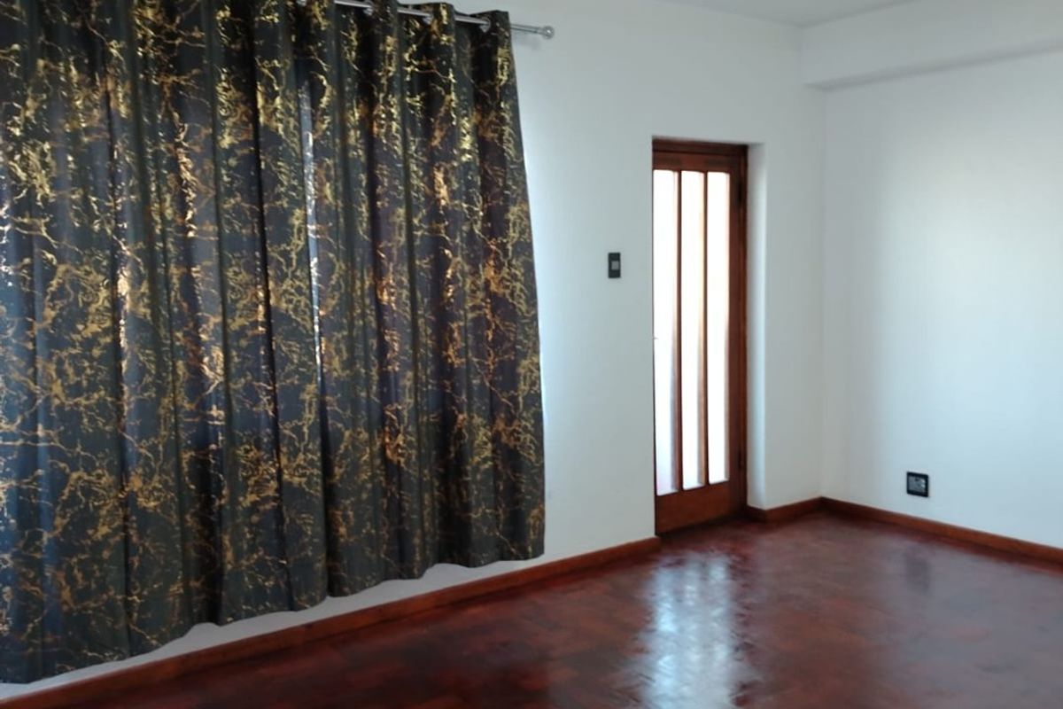 An empty bedroom featuring polished parquet flooring, a wooden door with glass inserts, and neutral white walls.