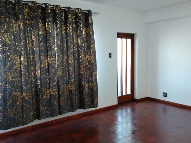 An empty bedroom featuring polished parquet flooring, a wooden door with glass inserts, and neutral white walls.