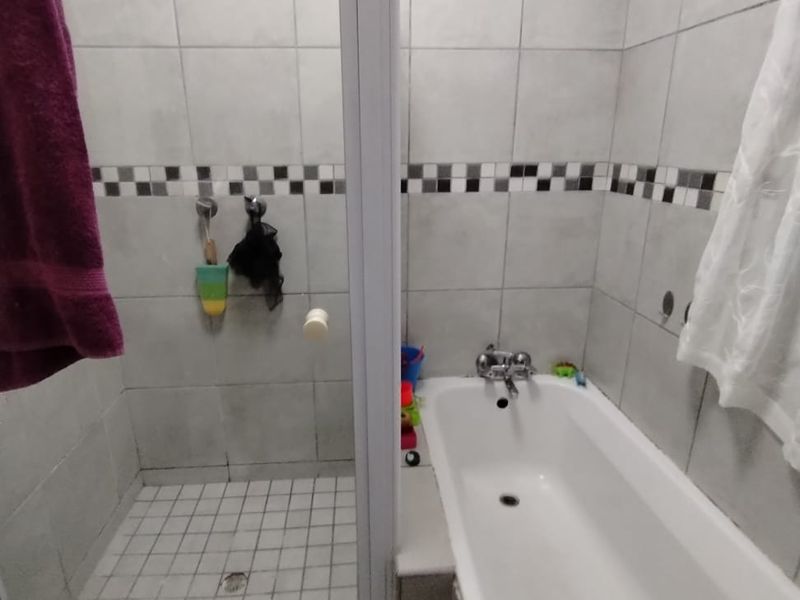 A functional bathroom featuring a separate shower enclosure and a bathtub with tiled walls and flooring.