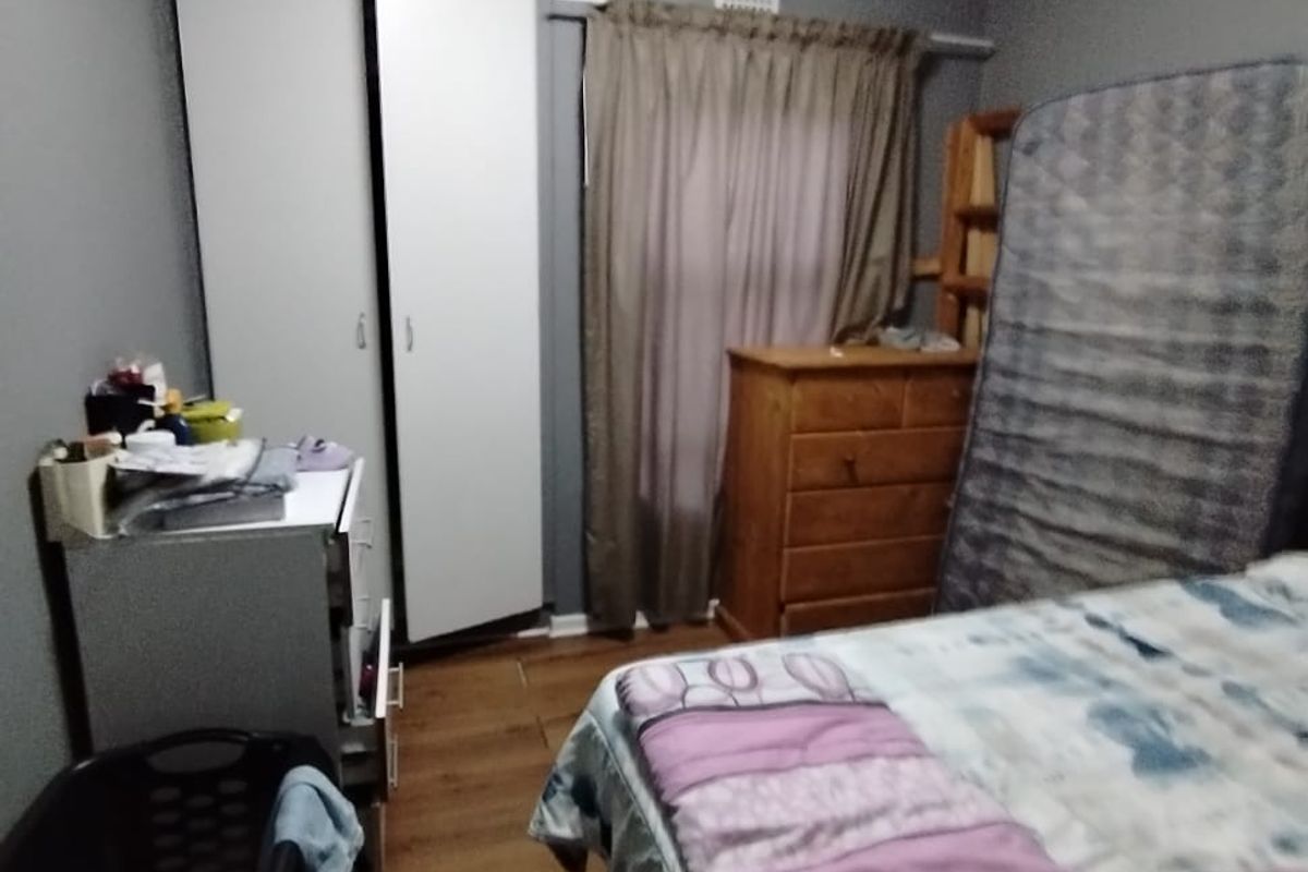 A bedroom featuring laminate flooring and a built-in wardrobe, providing functional storage space within the apartment.