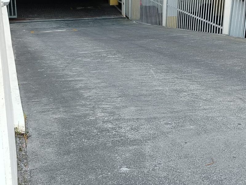 Entrance ramp leading to an underground parking garage with metal security gates and height restriction signage.