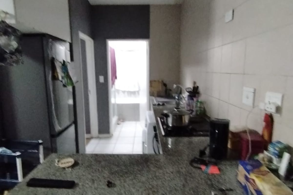 A compact kitchen featuring granite countertops, built-in cabinetry, and a tiled backsplash, with visible signs of ceiling water damage.
