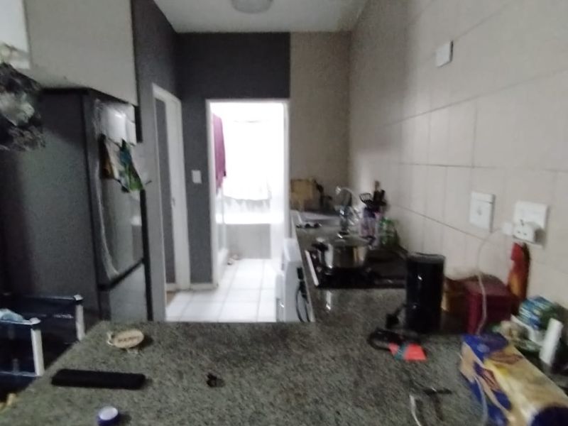 A compact kitchen featuring granite countertops, built-in cabinetry, and a tiled backsplash, with visible signs of ceiling water damage.