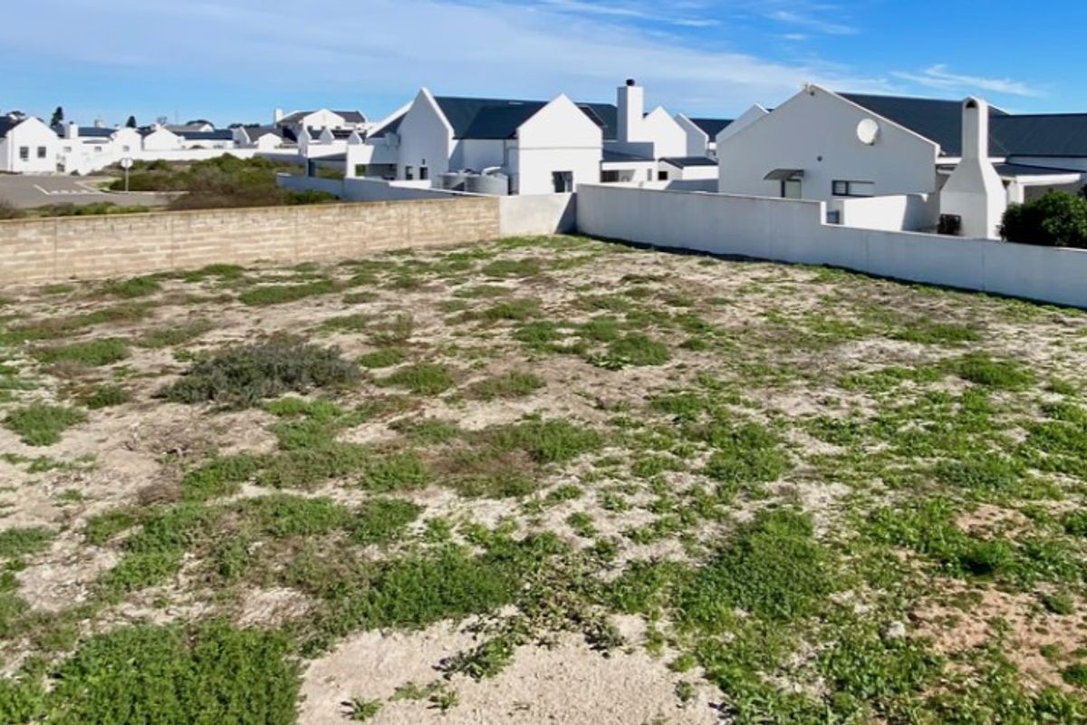 A vacant residential plot featuring established boundary walls and surrounding neighborhood development, offering a clear space for future construction.