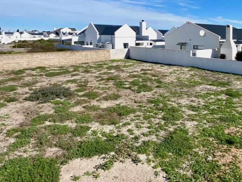 A vacant residential plot featuring established boundary walls and surrounding neighborhood development, offering a clear space for future construction.