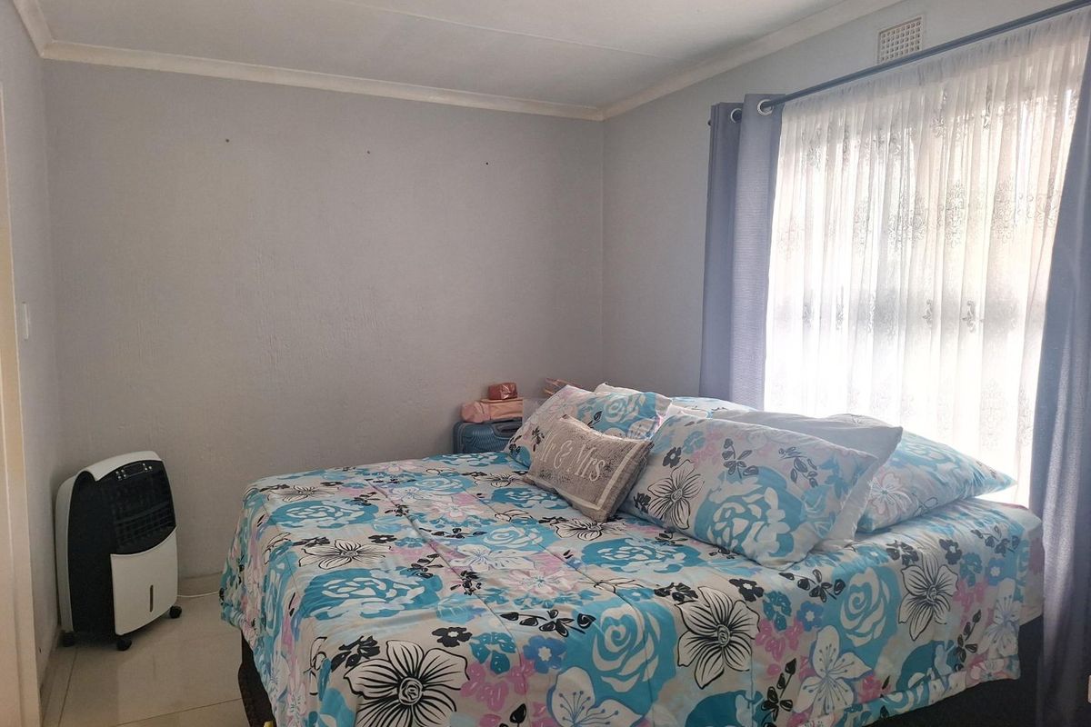 A bedroom featuring tiled flooring and a window with curtain treatments, providing a functional and neutral living space.