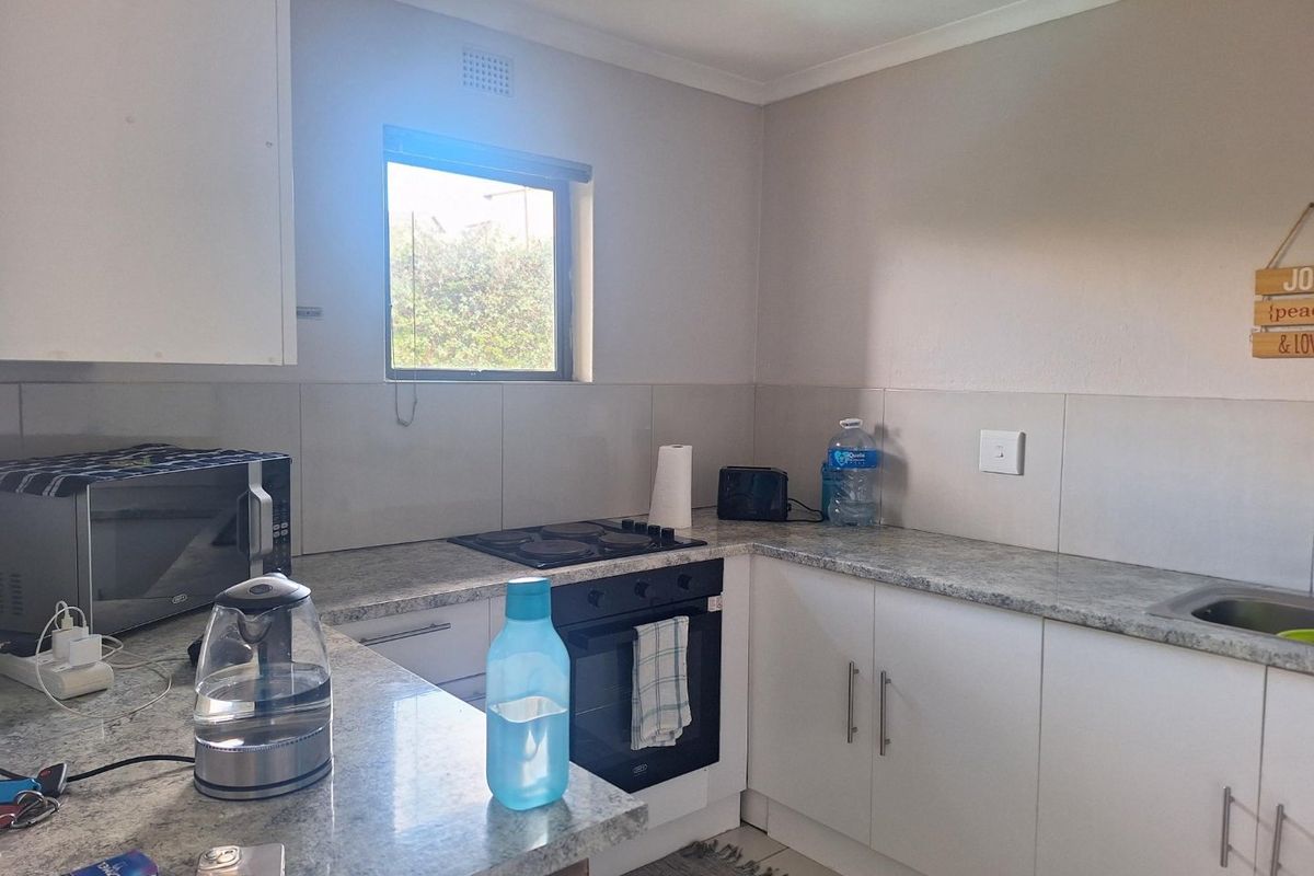 A functional kitchen featuring white cabinetry, granite countertops, a built-in oven, and an electric hob with a tiled backsplash.