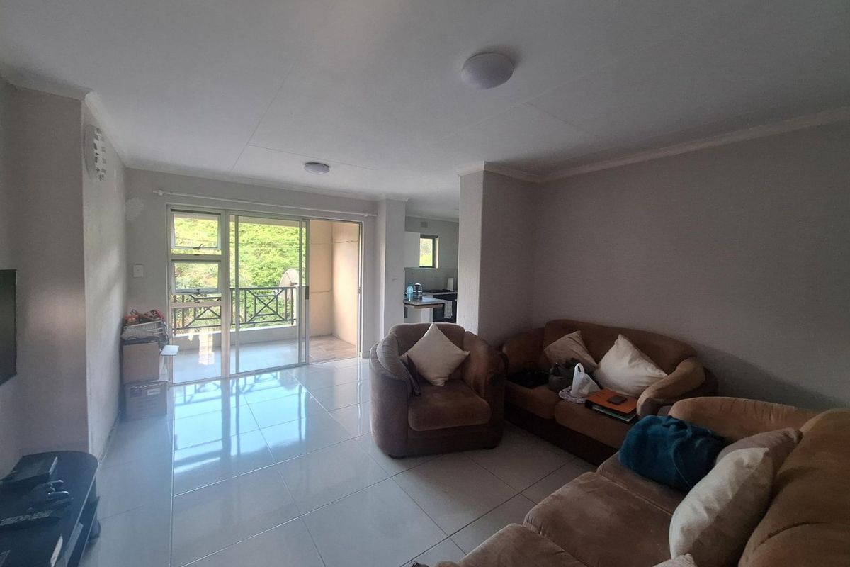Spacious living area with neutral tiled flooring and direct access to a private balcony through large sliding glass doors.