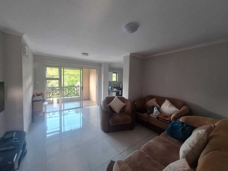 Spacious living area with neutral tiled flooring and direct access to a private balcony through large sliding glass doors.