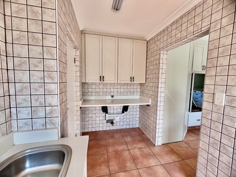 A functional laundry area featuring tiled walls and floors, built-in cabinetry, and dedicated plumbing connections for appliances.
