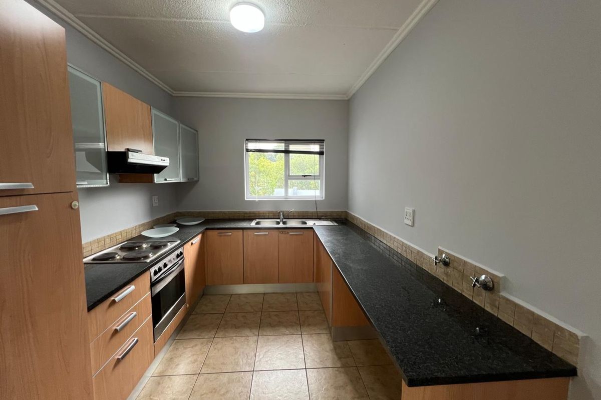 A functional kitchen featuring wood-finish cabinetry, granite countertops, an integrated stove and oven, and tiled flooring with dedicated plumbing for appliances.
