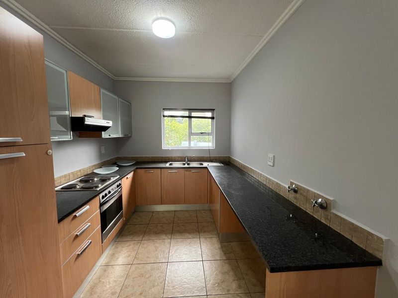 A functional kitchen featuring wood-finish cabinetry, granite countertops, an integrated stove and oven, and tiled flooring with dedicated plumbing for appliances.