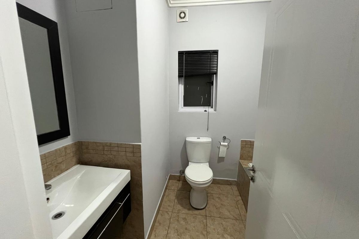 A clean and functional bathroom featuring a vanity basin, toilet, tiled flooring, and an extractor fan.