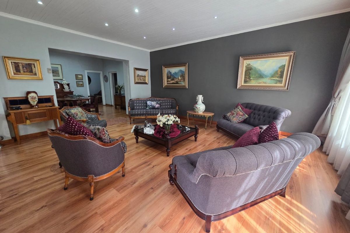 Spacious living room featuring warm timber flooring, a tongue and groove ceiling with recessed downlights, and a feature dark accent wall.