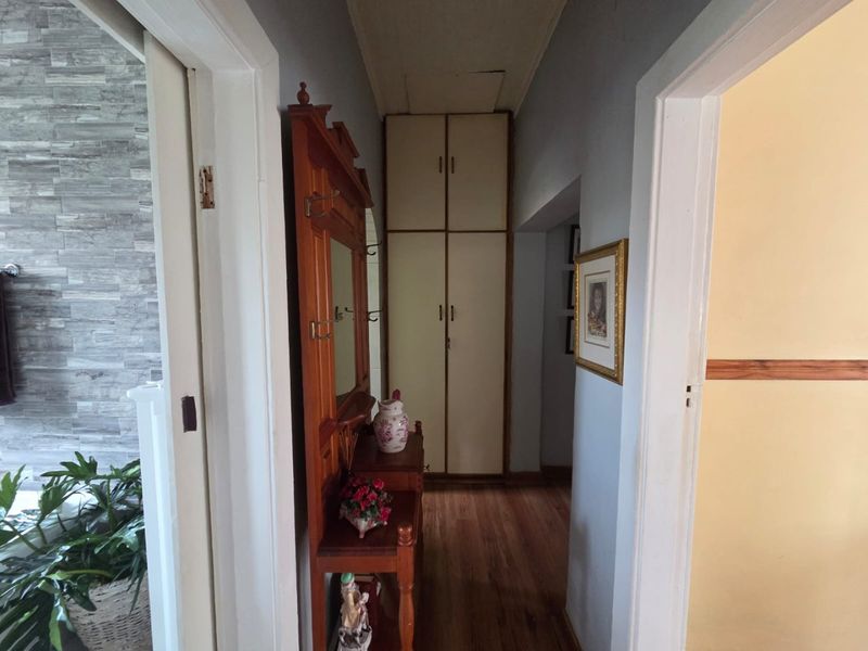 A narrow hallway featuring built-in storage cupboards and laminate flooring, showing signs of wear on the ceiling.