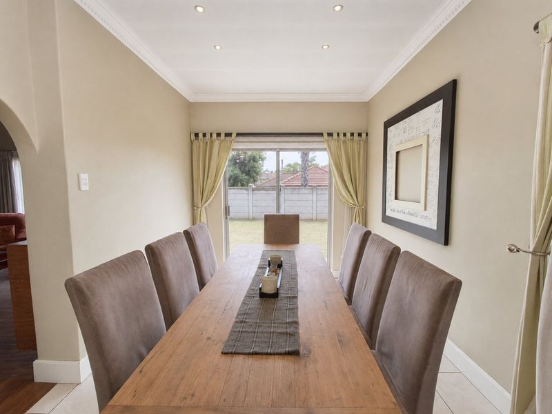 A well-lit dining room featuring crown molding, recessed downlights, tiled flooring, and a sliding glass door providing access to the rear garden.