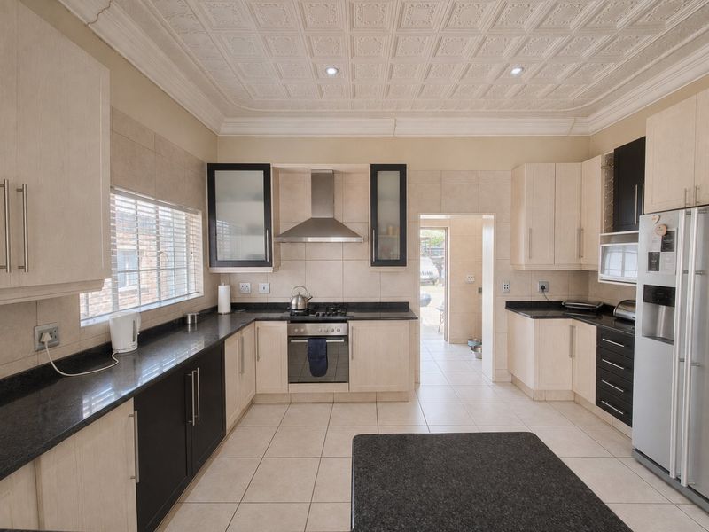 A functional kitchen featuring granite countertops, built-in cabinetry, a gas hob with extractor fan, and a decorative coffered ceiling.