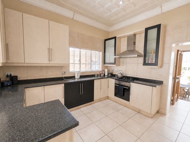 A well-maintained kitchen featuring light wood and black cabinetry, granite countertops, built-in oven and hob, and decorative ceiling tiles.