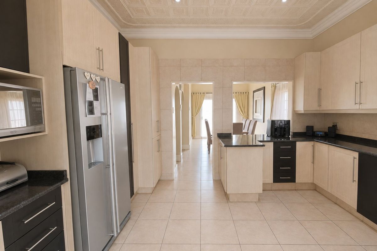 A well-maintained kitchen featuring light wood cabinetry, dark granite countertops, tiled flooring, and a decorative coffered ceiling with recessed lighting.