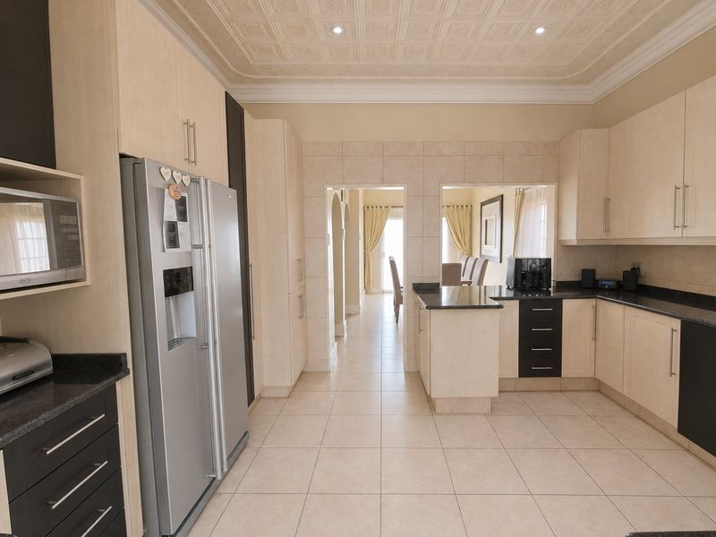 A well-maintained kitchen featuring light wood cabinetry, dark granite countertops, tiled flooring, and a decorative coffered ceiling with recessed lighting.