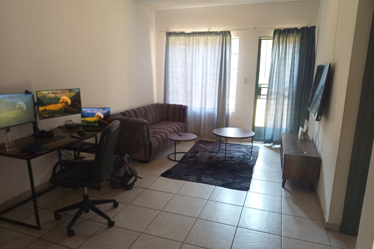 A functional living room featuring tiled flooring and a sliding glass door providing natural light and access to the exterior.