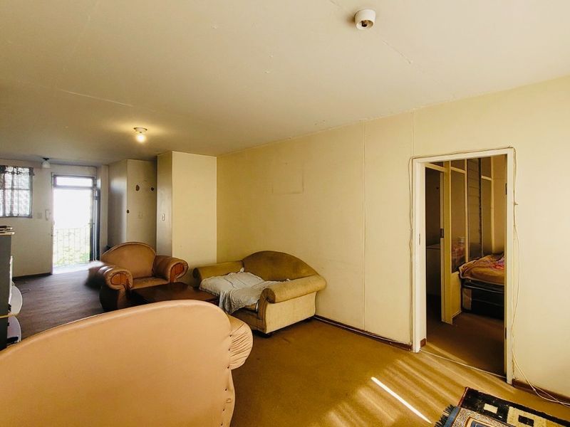 A dated living room area featuring carpeted flooring and access to an external balcony, requiring cosmetic updates to improve its overall appeal.