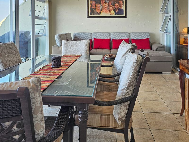 Enclosed balcony area featuring tiled flooring, large glass sliding doors, and expansive ocean views, suitable for use as a dining or lounge space.