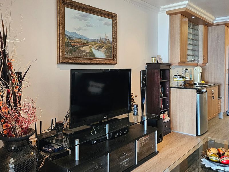 Open-plan living area featuring laminate flooring, recessed lighting, and a functional kitchen space with built-in cabinetry and granite countertops.