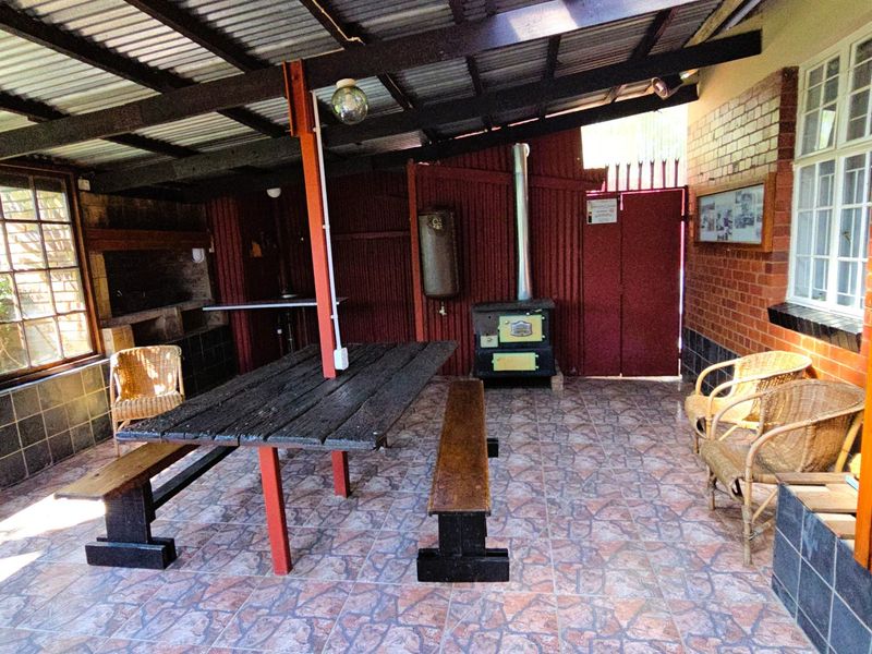 Covered outdoor patio area featuring a built-in braai, wood-burning stove, and tiled flooring, suitable for outdoor entertaining.