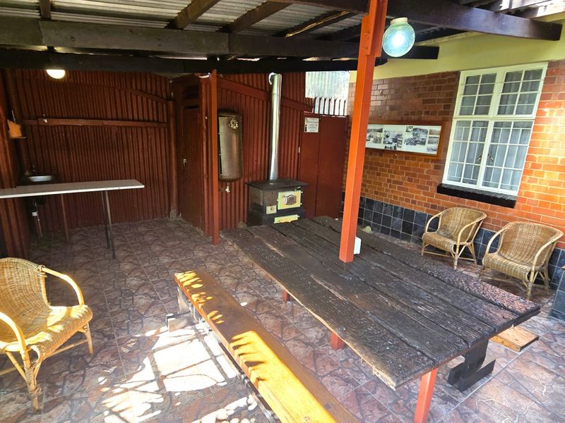 Covered outdoor patio area featuring a built-in braai, wood-burning stove, and tiled flooring, providing a rustic space for outdoor entertaining.