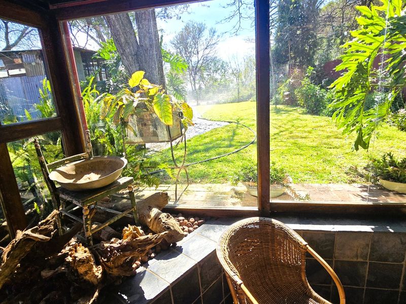 Enclosed patio area featuring large glass windows with views over the garden, providing a bright and tranquil space for relaxation.