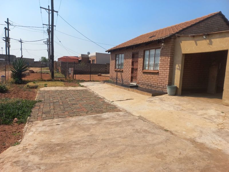 Front view of a face brick house featuring a tiled roof, concrete driveway, and an integrated carport area.