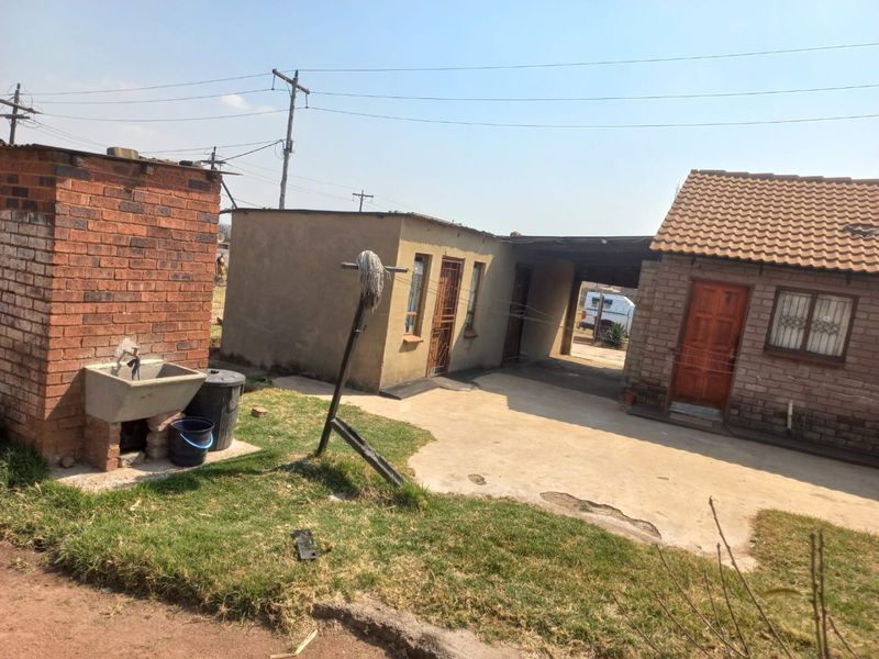 Rear exterior view showing a concrete driveway, brick outbuilding, and a standalone concrete wash basin area.