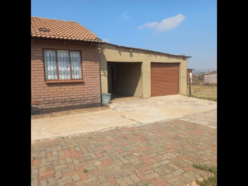 Front exterior view of a brick house featuring a tiled roof, security bars on windows, a single garage, and a paved driveway.
