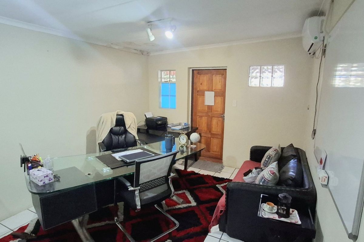 A functional office space featuring tiled flooring, an air conditioning unit, and a wall-mounted whiteboard, showing signs of ceiling water damage.
