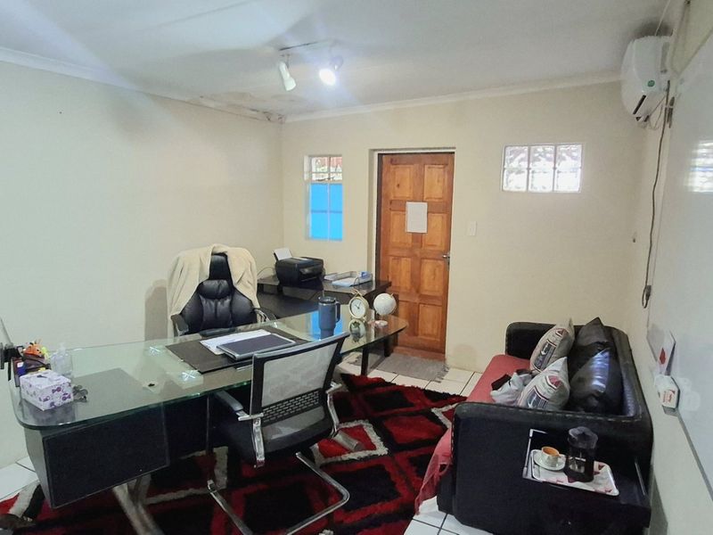 A functional office space featuring tiled flooring, an air conditioning unit, and a wall-mounted whiteboard, showing signs of ceiling water damage.