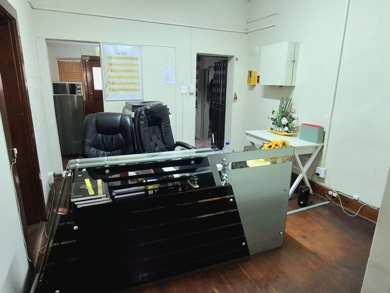 A functional commercial office space featuring timber flooring and neutral wall finishes, suitable for a reception or administrative work area.