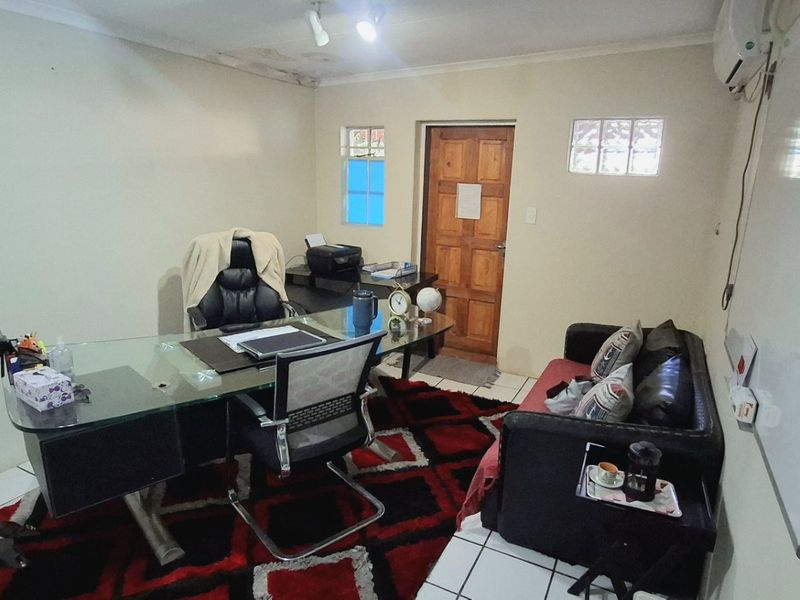 A functional office space featuring tiled flooring, a wall-mounted air conditioner, and a whiteboard, with visible signs of ceiling water damage.