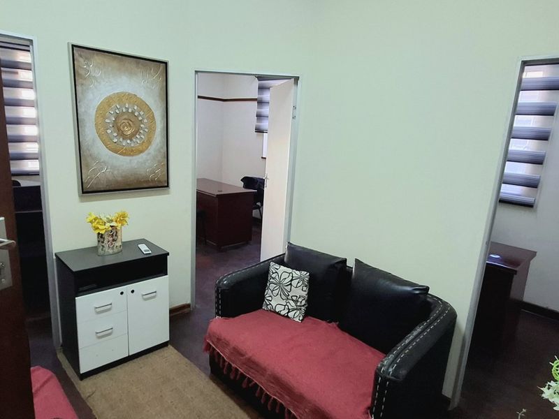 A functional office reception area featuring multiple doorways leading to private workspaces, equipped with modern zebra blinds and solid wood doors.